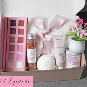 Puede incluir: Una caja de regalo que contiene una paleta de sombras de ojos rosa, un frasco de cristal con sales de ba&ntilde;o rosas, una bomba de ba&ntilde;o blanca, un tubo de crema de manos de vainilla y rosa, una vela de ramo de rosas y una manta blanca con lazo rosa.