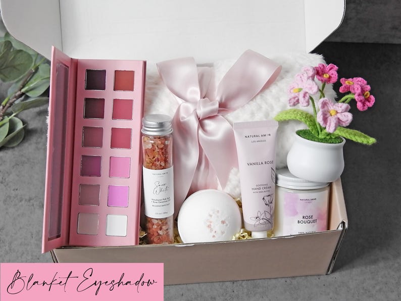 Puede incluir: Una caja de regalo que contiene una paleta de sombras de ojos rosa, un frasco de cristal con sales de ba&ntilde;o rosas, una bomba de ba&ntilde;o blanca, un tubo de crema de manos de vainilla y rosa, una vela de ramo de rosas y una manta blanca con lazo rosa.