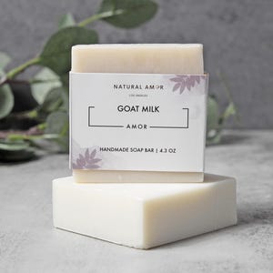 May include: A white bar of goat milk soap with a label that reads "Natural Amor Los Angeles Goat Milk Amor Handmade Soap Bar | 4.3 oz"