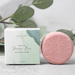 May include: A pink shampoo bar with the text "Amino Acid Shampoo Bar Organic Moist Treatment" and "Natural Am'r" on the packaging. The bar is 2 oz or 60 g.