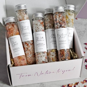 May include: A white box with the text "From Nature to you!" printed on the front. The box contains six glass tubes filled with bath salts. The tubes are labeled with different names, such as "Snow White", "Sleeping Beauty", and "The Little Mermaid".