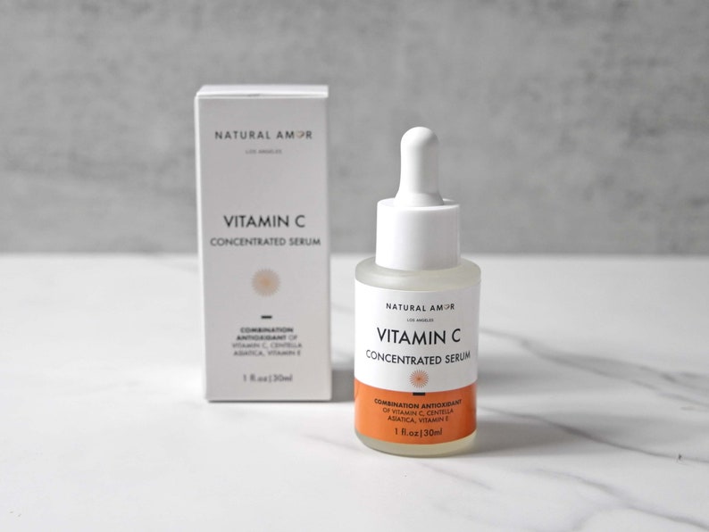 May include: A white bottle and box of Vitamin C Concentrated Serum by Natural Amor. The bottle has a white dropper and a clear liquid. The box and bottle both have the text "Vitamin C Concentrated Serum". The box and bottle also have the text "1 fl.oz | 30ml".