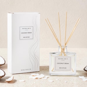 May include: A white box and a clear glass reed diffuser with the text "COCONUT CREAM" and "REED DIFFUSER". The diffuser has wooden reeds and is next to a box and coconut halves. The box reads "100 ML / 3.34 FL OZ".