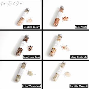 May include: Five clear glass tubes filled with different colored bath salts. The tubes are labeled with the names "Sleeping Beauty", "Snow White", "Beauty and Beast", "Glory Cinderella", and "In the Wonderland".
