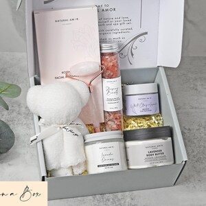 Puede incluir: Una caja de regalo que contiene un oso de peluche blanco, un rodillo facial rosa, un tubo de sales de ba&ntilde;o rosas, un tarro de mascarilla de arcilla blanca y lavanda, una vela de lavanda y un tarro de manteca corporal de lavanda.