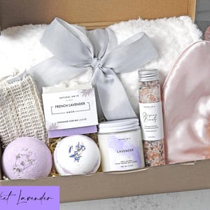 Puede incluir: Una caja de regalo que contiene una manta de piel sint&eacute;tica blanca con una cinta gris, un antifaz de sat&eacute;n rosa, un jab&oacute;n de lavanda francesa, dos bombas de ba&ntilde;o redondas, una vela de soja de lavanda y sales de ba&ntilde;o rosas.
