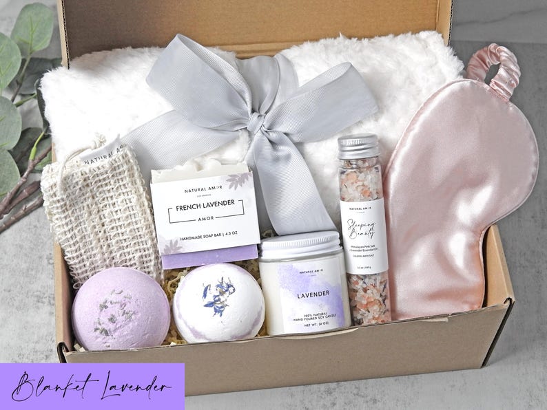 Puede incluir: Una caja de regalo que contiene una manta de piel sint&eacute;tica blanca con una cinta gris, un antifaz de sat&eacute;n rosa, un jab&oacute;n de lavanda francesa, dos bombas de ba&ntilde;o redondas, una vela de soja de lavanda y sales de ba&ntilde;o rosas.