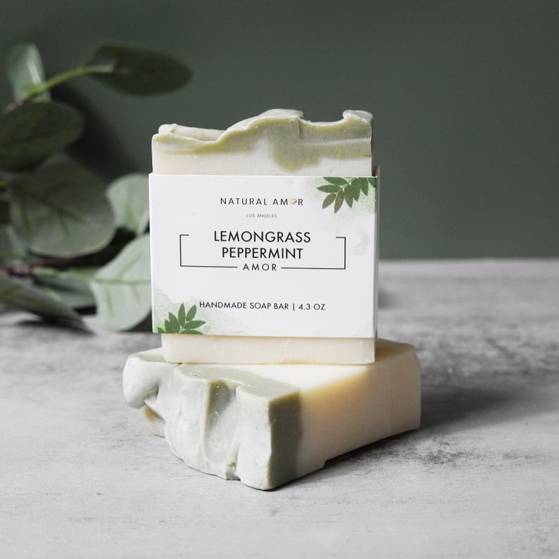 May include: A white and green bar of handmade soap with the text "Lemongrass Peppermint - Amor" and "Natural Amor Los Angeles" on the label. The soap bar is 4.3 oz.