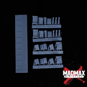 May include: Four sprues of grey plastic model kits for a Mad Max themed miniature game. The sprues contain various items, including flags, books, and other objects. The sprues are labelled "Mad Max Miniature".