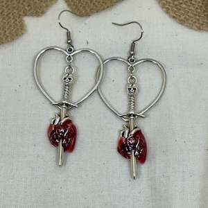 para czerwonych kolczyków w kształcie serca z mieczem/sztyletami