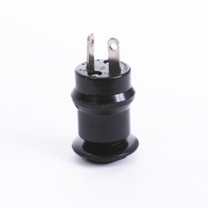 May include: A black electrical plug adapter with two metal prongs and a rounded base. The adapter is cylindrical with a slightly wider midsection and a small, circular base. The prongs are silver and have small holes.