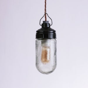 May include: A black and clear glass pendant light with a textured glass shade and a brown cord.