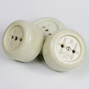 May include: Three off-white round electrical outlet covers with two holes each. The cover on the right has the text "6A 250V YXB1.4" printed on it.