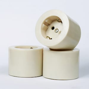 May include: Three off-white plastic electrical outlet covers with a round shape.