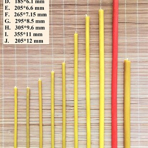 May include: Ten beeswax candles of varying lengths, ranging from 5.1 to 12 inches, arranged in a row on a woven bamboo mat. The candles are all yellow except for the last one, which is red.