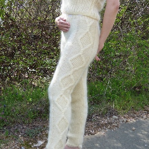 May include: White knitted pants with a diamond pattern. The pants are made of a soft, fluffy material.