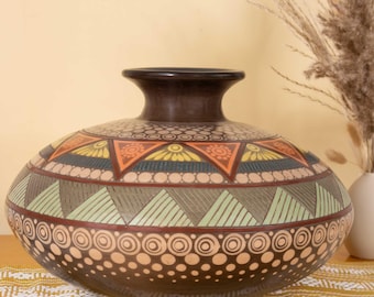 May include: A wide, dark brown ceramic vase featuring a rounded body and a narrow neck. The surface is decorated with horizontal bands of geometric patterns, including triangles, circles, and sunburst motifs in shades of orange, yellow, and green.