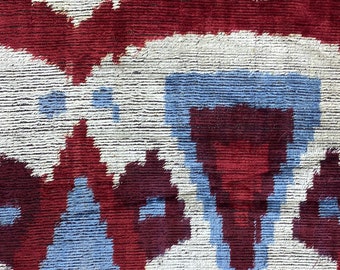 May include: Close-up of a woven fabric with a repeating pattern of white, blue, and burgundy shapes. The fabric has a textured surface.
