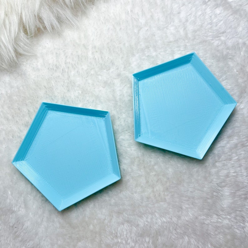 May include: Two light blue, geometrically shaped trays with a textured surface. The trays are made of a smooth, hard material and have a slightly raised edge.