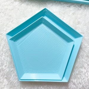 May include: Two light blue, geometrically shaped trays, one nested inside the other. The trays are made of a smooth, plastic-like material and have a slightly textured surface.