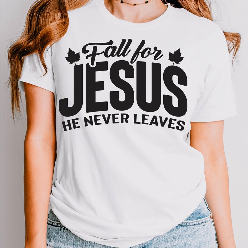 May include: White t-shirt with the text "Fall for JESUS He Never Leaves" in black. The word "JESUS" is in a bold, large font. The shirt has short sleeves and a crew neck.