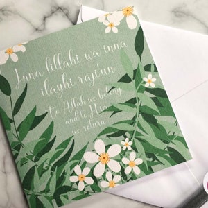 Puede incluir: Una tarjeta verde con flores blancas y el texto "Inna lillahi wa inna ilayhi raji'un"  "To Allah we belong and to Him we return".