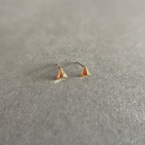 K&ouml;nnte beinhalten: Ein Paar goldene Dreiecks-Ohrstecker. Die Ohrringe sind klein und zart.