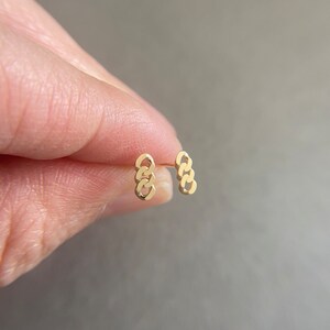 May include: A pair of gold chain link earrings. The earrings are small and delicate, and they are perfect for everyday wear.