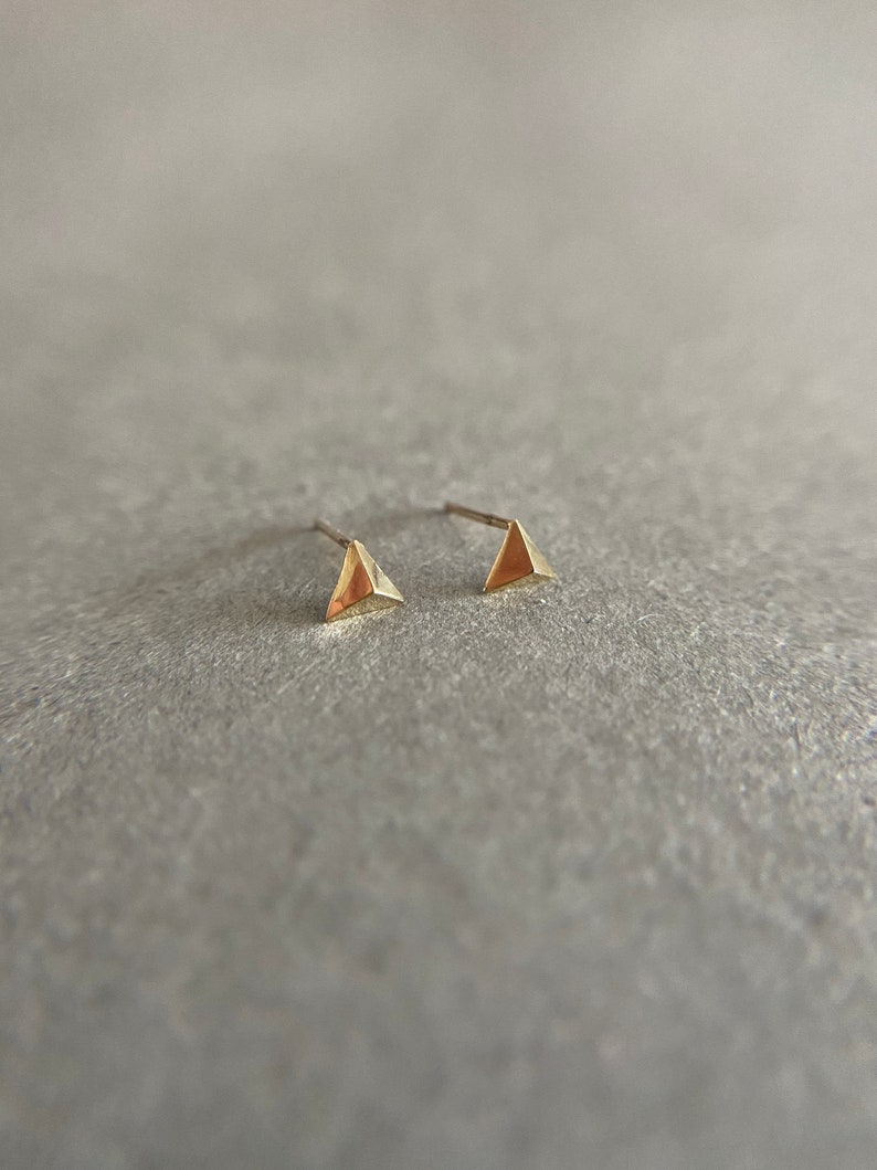 K&ouml;nnte beinhalten: Ein Paar goldene Dreiecks-Ohrstecker. Die Ohrringe sind klein und schlicht und w&uuml;rden eine gro&szlig;artige Erg&auml;nzung f&uuml;r jede Schmucksammlung sein.