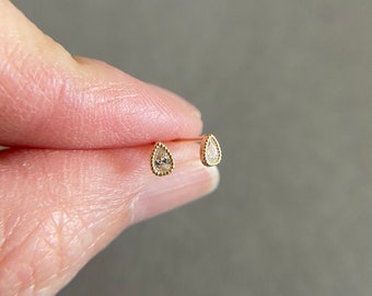 Könnte beinhalten: Ein Paar goldene Ohrringe in Tropfenform mit kleinen, klaren Steinen in der Mitte.