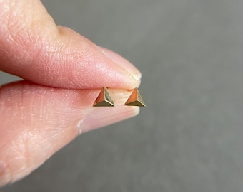 May include: A pair of gold triangle stud earrings.