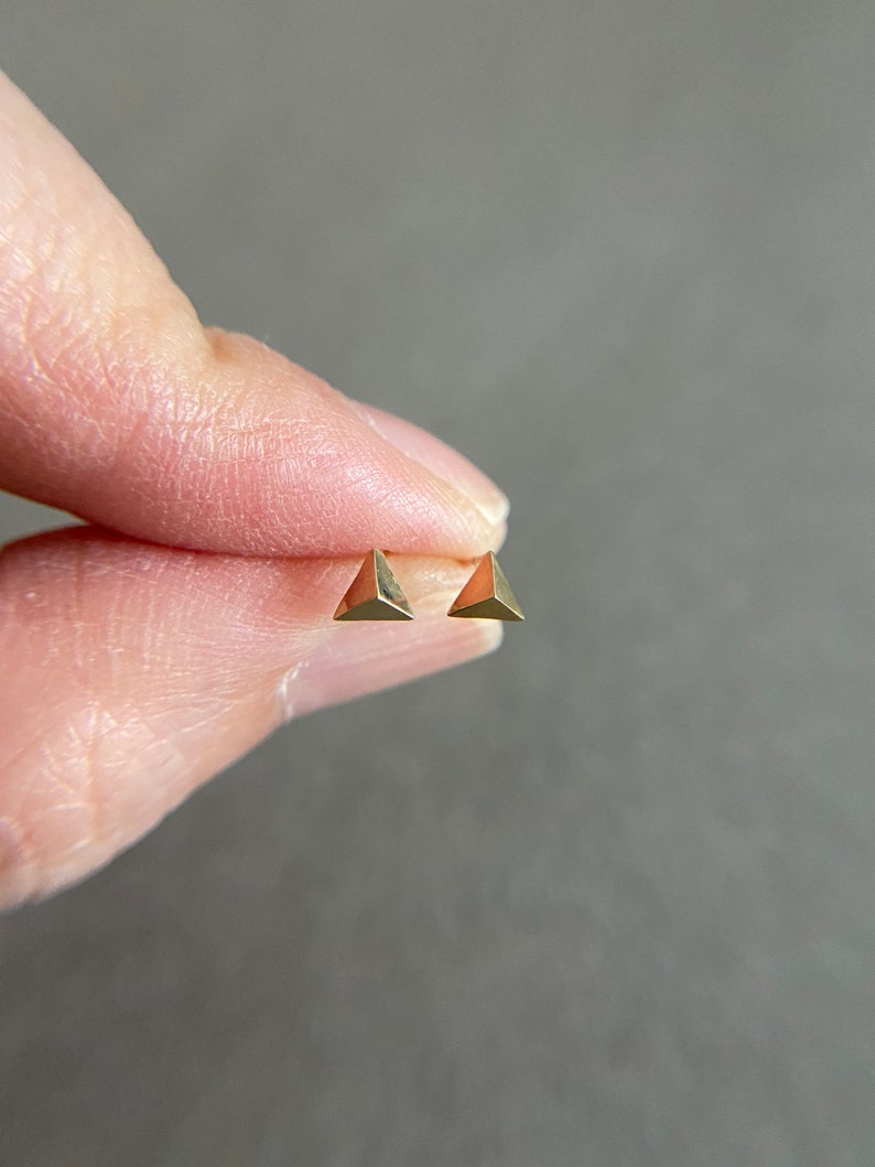 K&ouml;nnte beinhalten: Ein Paar goldene Dreiecks-Ohrstecker.
