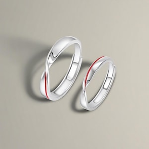 Peut inclure: Deux bagues de couleur argentée avec une finition polie et lisse et un design torsadé subtil. Chaque bague est accentuée par une fine ligne rouge vive courant le long du centre de l'anneau, créant un contraste distinct avec la surface métallique.