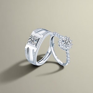Op de afbeelding: Een paar zilveren ringen met heldere edelstenen. De ring aan de linkerkant heeft een vierkante zetting met een grotere edelsteen, terwijl de ring aan de rechterkant een ronde zetting heeft met een kleinere edelsteen.
