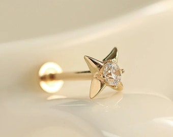 May include: Gold star shaped nose piercing with a clear gemstone in the center.