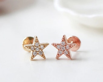 May include: Two star-shaped earrings with clear cubic zirconia stones. The earring on the left is gold-toned, and the earring on the right is rose gold-toned.