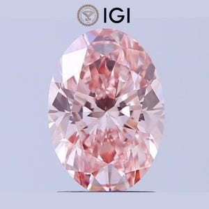 May include: An oval-shaped, faceted pink diamond. The gemstone has a high degree of clarity and brilliance, with a light pink hue. The IGI logo is visible in the upper left corner.