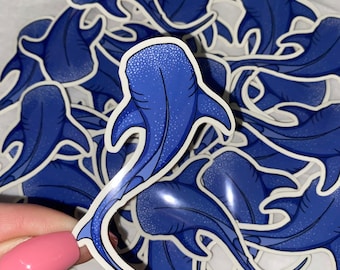 May include: A stack of blue whale shark stickers with a white outline. The stickers are printed with a white speckled pattern.