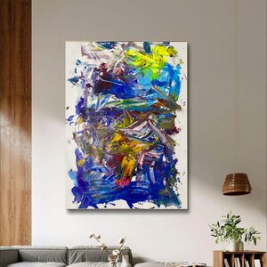 May include: Abstract painting with bold strokes of blue, yellow, white, and red paint. The painting has a textured, layered look.