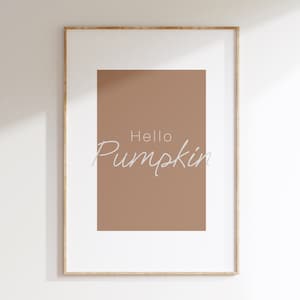 Könnte beinhalten: Ein gerahmter Druck mit braunem Hintergrund und dem Text "Hello Pumpkin" in Weiß.
