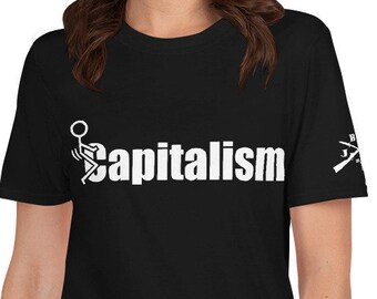 May include: Black t-shirt with the word "capitalism" in white, and a graphic of a person with a baseball bat. The shirt has a crew neck and short sleeves. A small graphic is on the right sleeve.