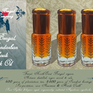May include: Three small glass bottles with gold lids and labels containing a dark amber liquid. The bottles are arranged in a row on a sandy background. The label on the bottles reads "Royal Bengal, Wild Bandarban Patchouli Prakritik Oil". The text on the label also reads "Finest. North-East Bengal region, Artisan distilled, agar wood & oils. 400 years of plantation ties. 3500 years of Sanskrit heritage Prepartition, rare Anamese & Hindi Oudh. Pure Sylhet 25 year aged, organically, cultivated Aquilaria agallocha".