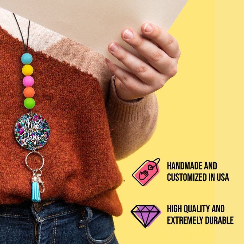 May include: A colourful beaded lanyard with a round, glittery charm that says "Miss Dance". The charm is attached to a key ring with a blue tassel. The lanyard is handmade and customised in the USA.