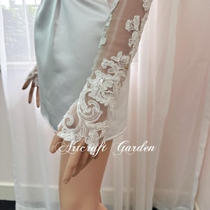 May include: White lace sleeves with floral embroidery. The sleeves are sheer, with intricate detailing and a delicate design. The text "Artcraft Garden" is visible at the bottom of the image.