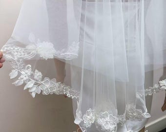 May include: White bridal veil with delicate floral lace trim. The veil is made of soft tulle and has a single layer.