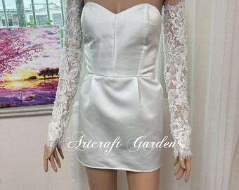 May include: A white satin mini dress with a sweetheart neckline and a fitted bodice. The dress features detachable long lace sleeves. The text "Artcraft Garden" is printed on the dress.