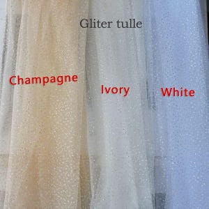 May include: Close-up of glitter tulle fabric in champagne, ivory, and white. The fabric is semi-transparent and has a sparkling effect. The text "Gliter tulle" is visible at the top of the image, with the colors labeled below.