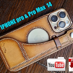 Könnte beinhalten: Eine braune Leder-Handyhülle mit einem gesteppten Design und einem Ausschnitt für die Kamera. Die Hülle ist für das iPhone Pro und Pro Max 14 konzipiert. Die Hülle hat einen Riemen an der Seite und eine kleine Tasche auf der Vorderseite. Der Text "HATA LEATHER" ist auf der Vorderseite der Hülle sichtbar.