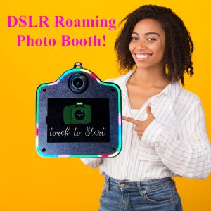 May include: A black DSLR roaming photo booth with a central lens and a screen displaying a green camera icon and the text touch to Start. The device features a colorful LED light border and is presented against a solid yellow background.