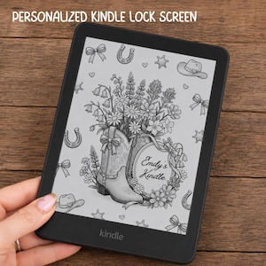 May include: A black e-reader displaying a personalized lock screen with a line art illustration of a cowboy boot filled with wildflowers, a floral wreath frame containing the text Emily's Kindle, and scattered western icons like hats and horseshoes.